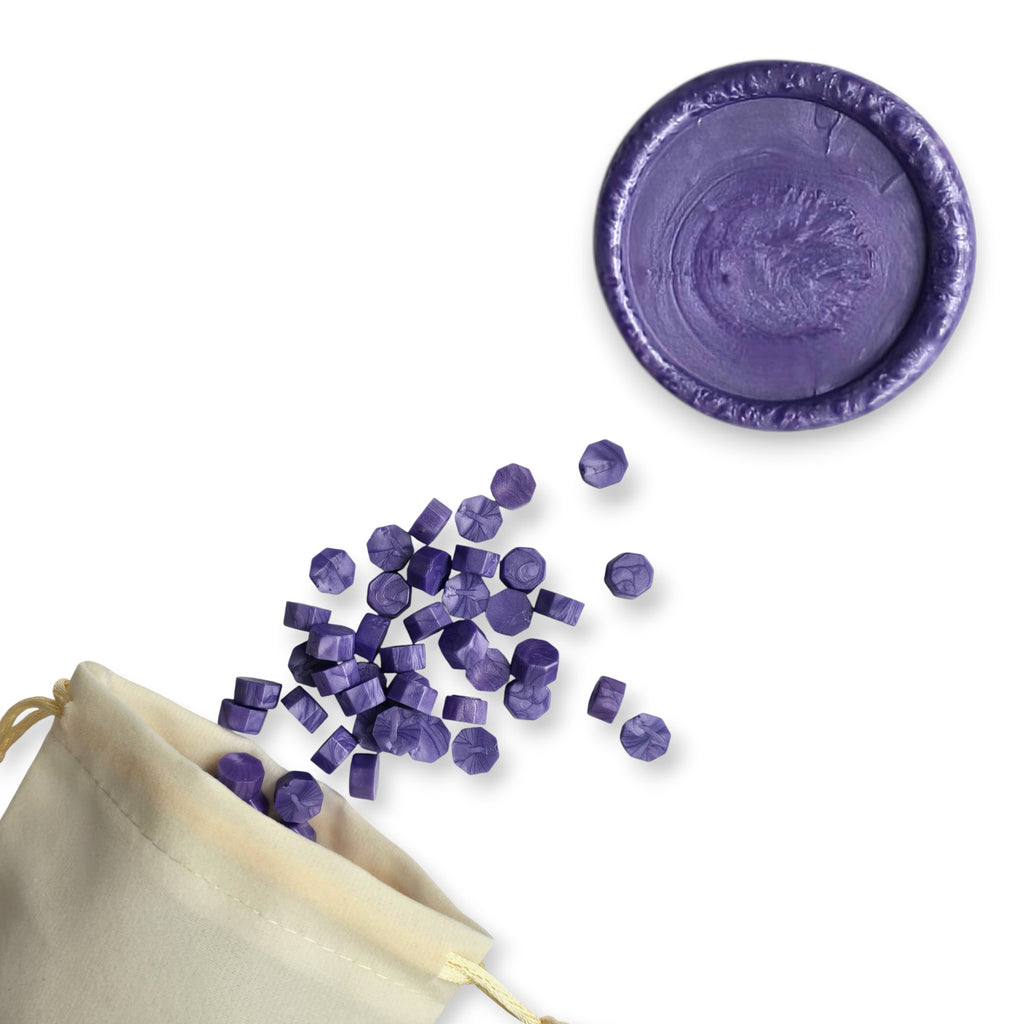 Amethyst wax beads spilling out of a beige drawstring bag onto a white background. In the top right corner is a blank wax seal in the showcasing the amethyst colour option.