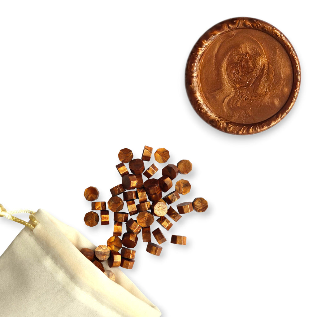 Copper wax beads spilling out of a beige drawstring bag onto a white background. In the top right corner is a blank wax seal in the showcasing the copper colour option.