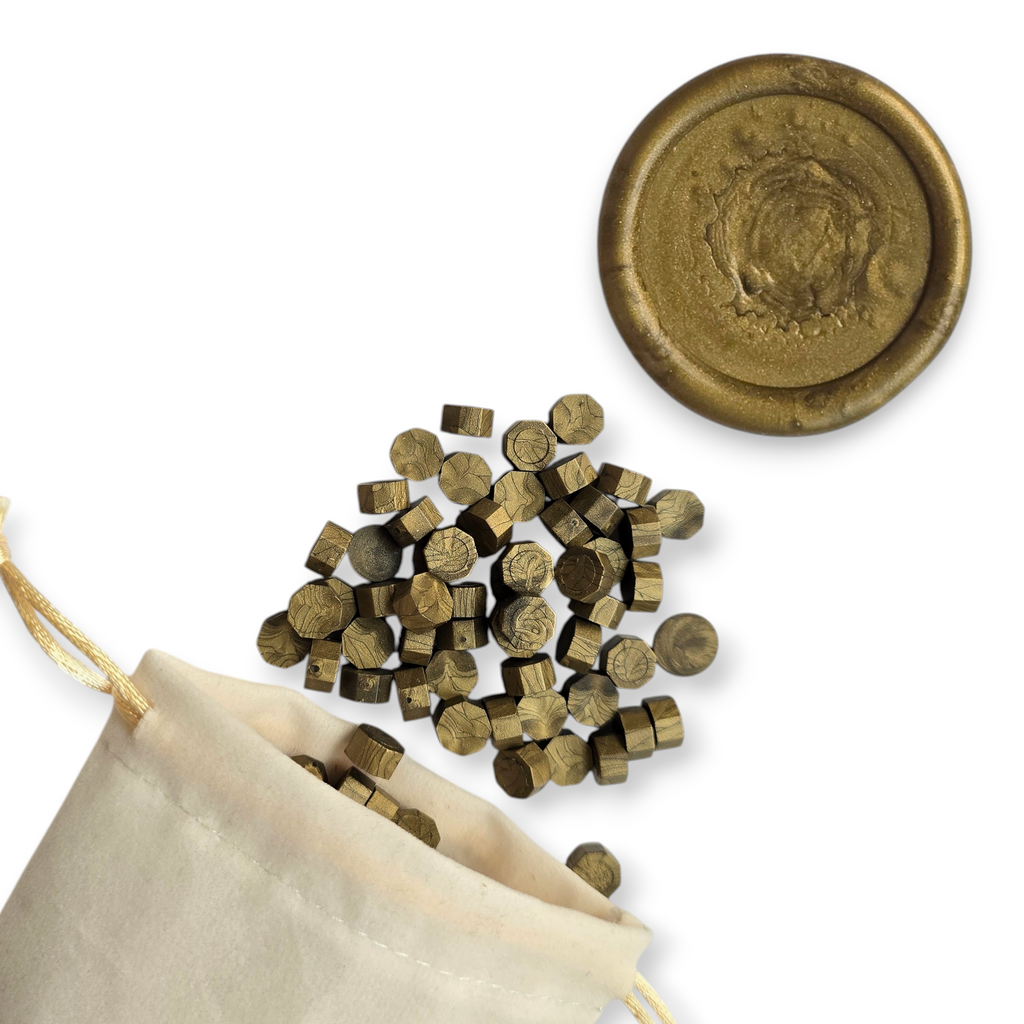 Emerald wax beads spilling out of a beige drawstring bag onto a white background. In the top right corner is a blank wax seal in the showcasing the emerald colour option.