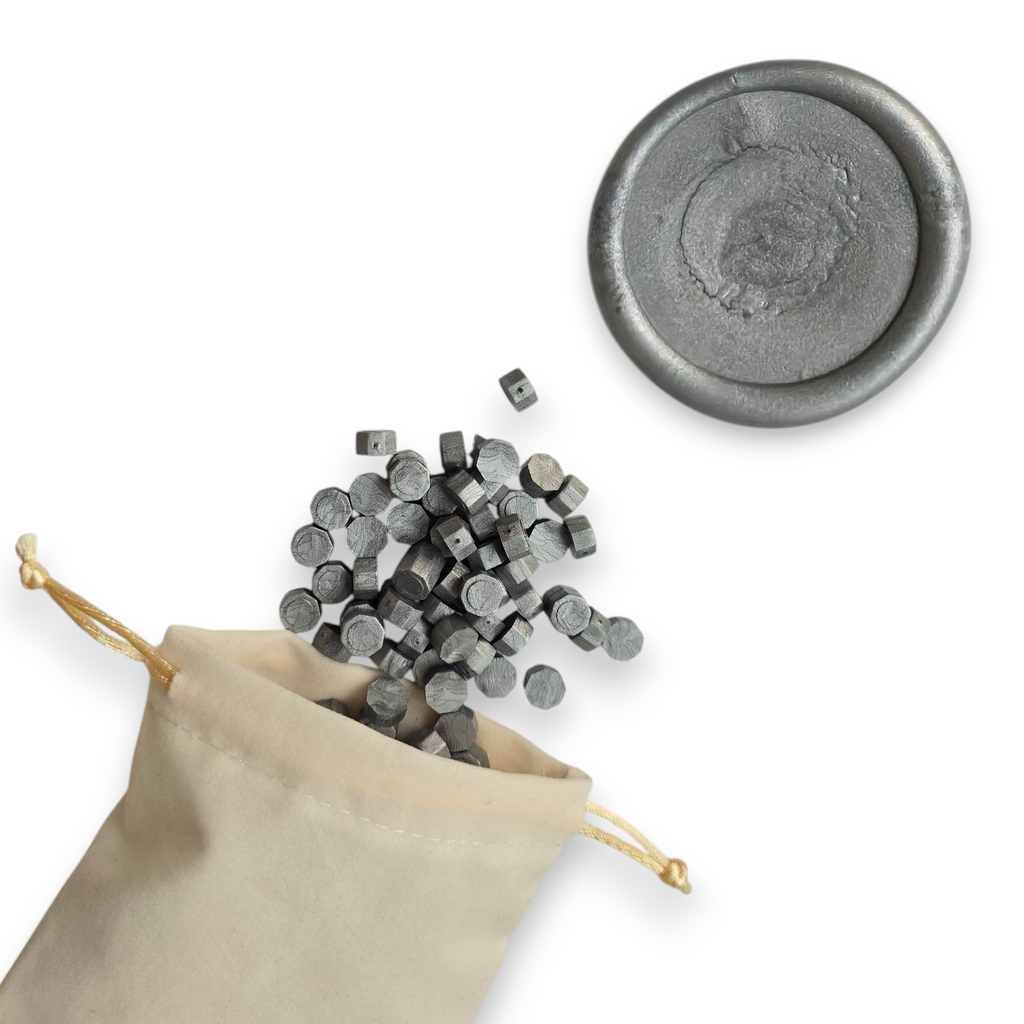 Silver wax beads spilling out of a beige drawstring bag onto a white background. In the top right corner is a blank wax seal in the showcasing the silver colour option.
